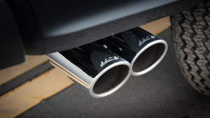 Close-up of a car's dual exhaust pipes with a visible brand logo.