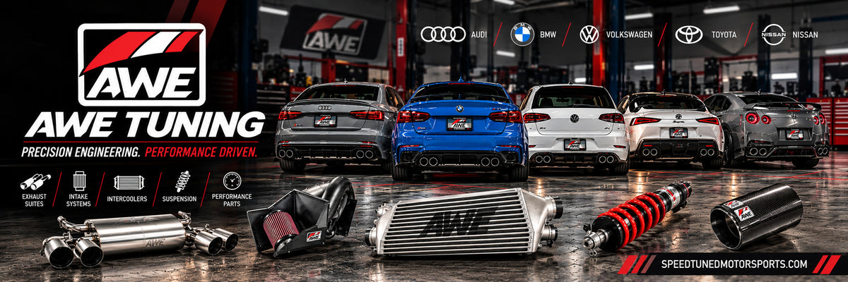 AWE Tuning performance parts collection at Speed Tuned Motorsports featuring exhaust systems, cold air intakes, intercoolers, and suspension components, with Audi, BMW, Volkswagen, Toyota Supra, and Nissan GT-R vehicles displayed in a professional automotive workshop.